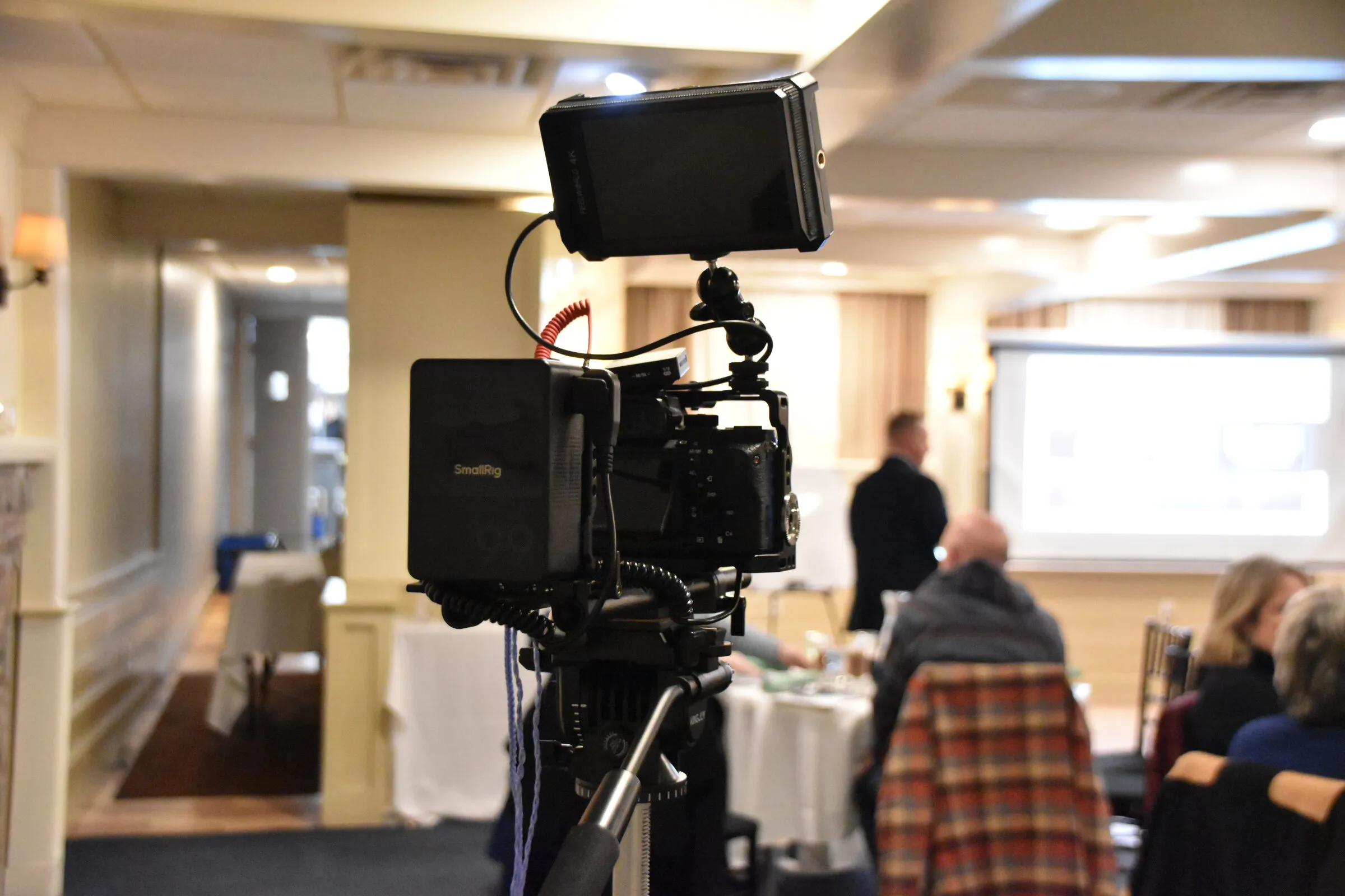 Camera with an external monitor filming a presentation in a function room