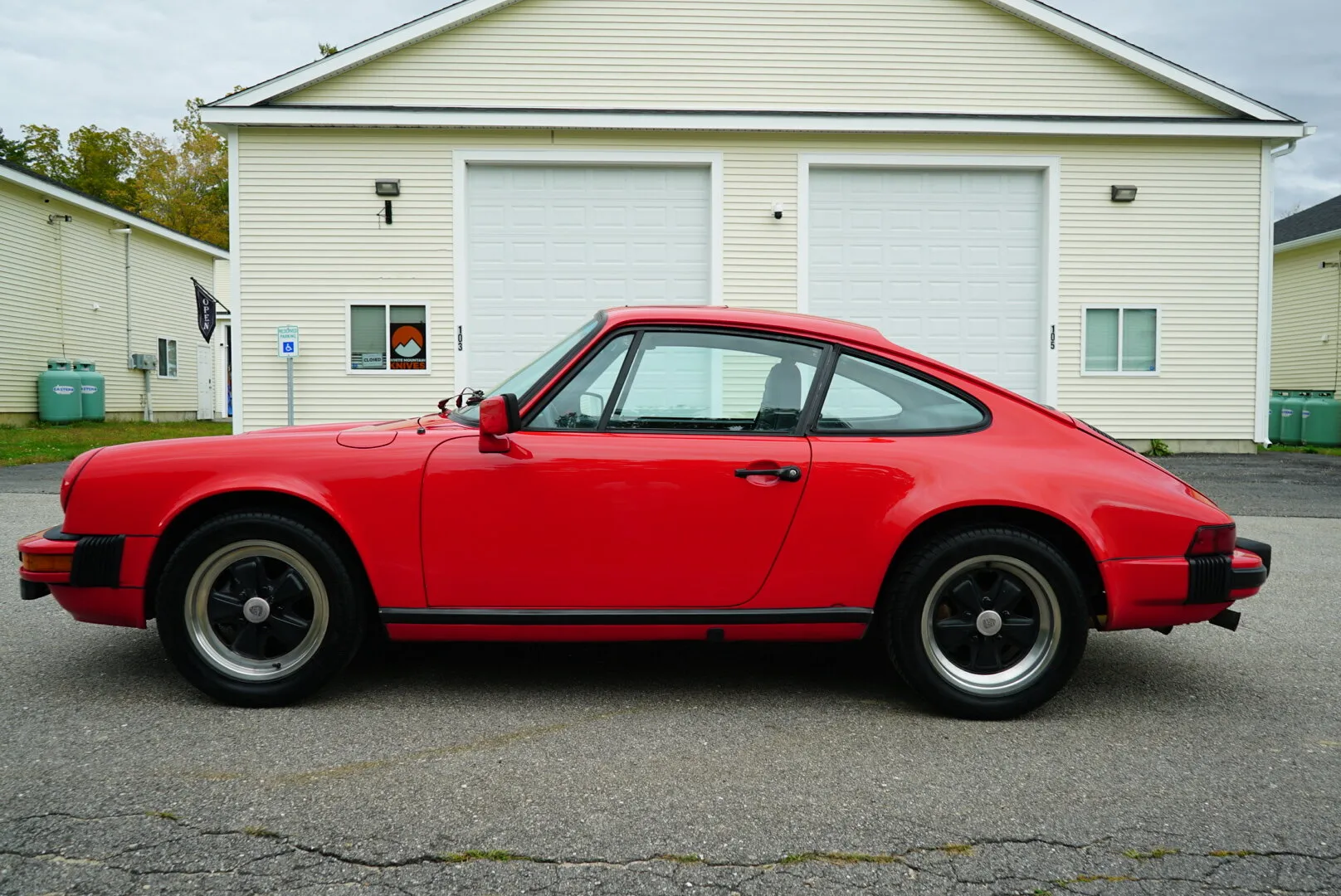Side profile of the red 911 SC in front of a garage